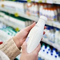 Person hält Milchflasche im Supermarkt fest